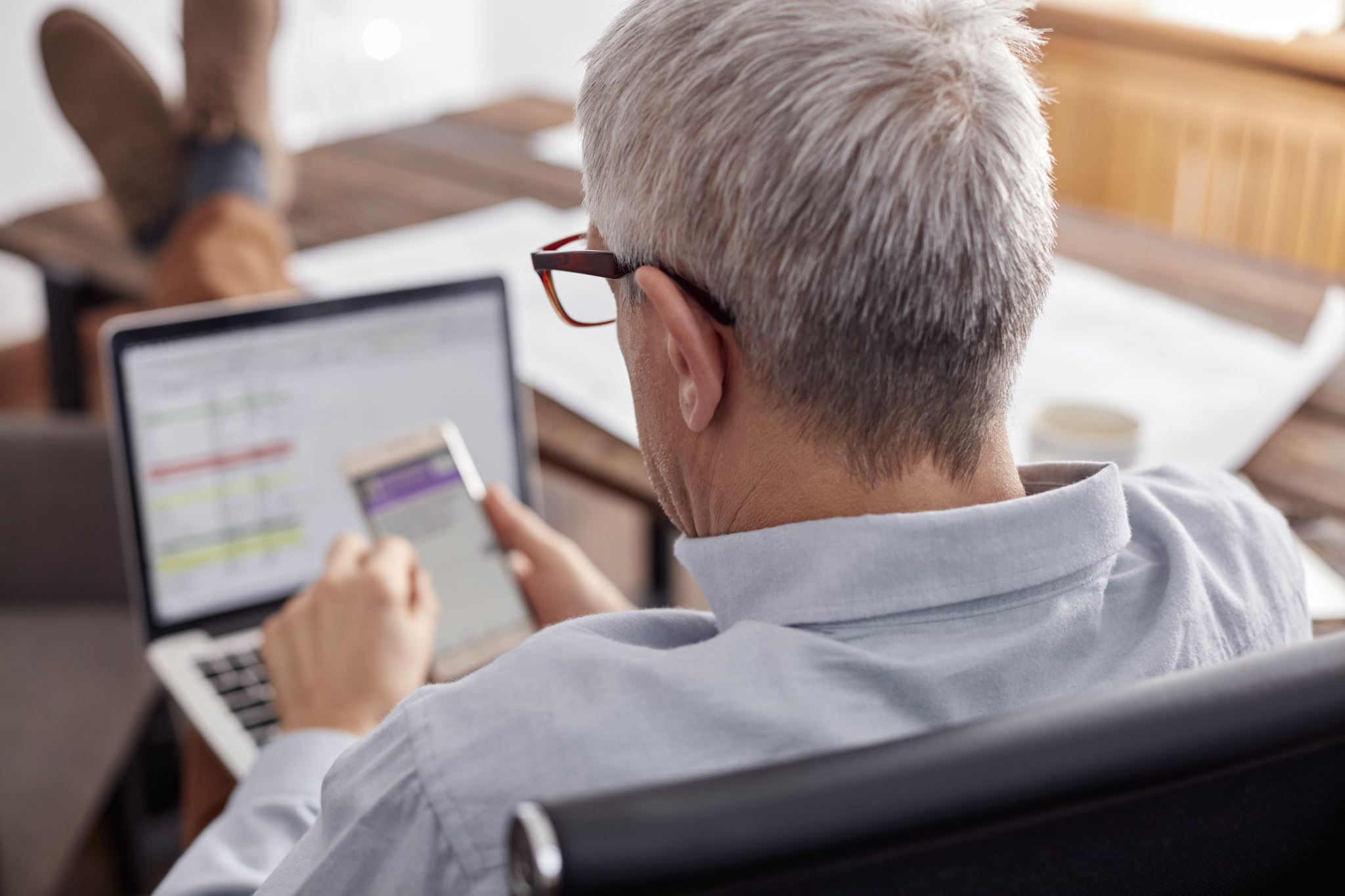 Homem-de-negócios-na-sala-de-estar-trabalhando-no-telefone-e-no-laptop-2